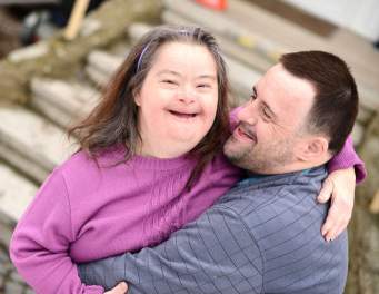 A girl with Downs Syndrome hugging her father